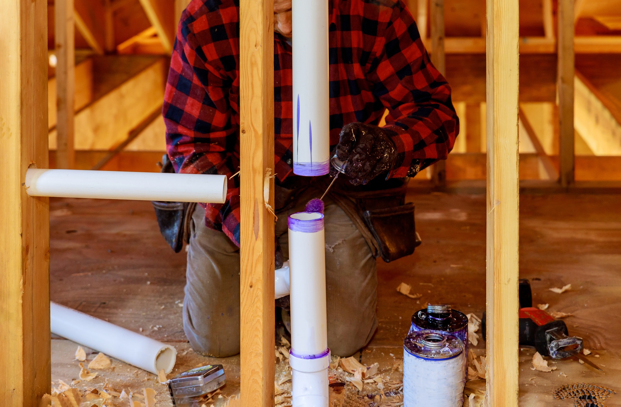 A Plumber applying primer and glue a PVC pipe drain assembly