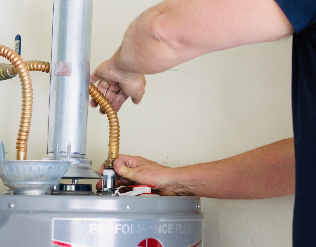 Adult male making adjustments and tightening connections on new hot water heater